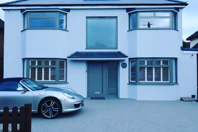 Photo of a medium sized and gey modern render detached house in London with a pitched roof and a tiled roof.