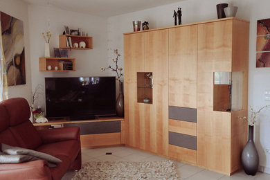 Ejemplo de sala de estar cerrada contemporánea de tamaño medio con paredes blancas, televisor en una esquina y suelo blanco