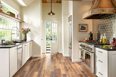 Design ideas for a mid-sized country galley separate kitchen in Atlanta with an undermount sink, shaker cabinets, white cabinets, quartz benchtops, metallic splashback, subway tile splashback, stainless steel appliances, dark hardwood floors, no island, brown floor and grey benchtop.