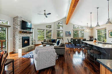 Photo of a mid-sized transitional open concept living room in Other with white walls, medium hardwood floors, a standard fireplace, a stone fireplace surround, a wall-mounted tv and brown floor.