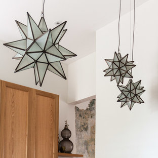 Cette image montre une arrière-cuisine victorienne en L de taille moyenne avec un évier intégré, un placard à porte vitrée, des portes de placard en bois clair, un plan de travail en inox, une crédence blanche, une crédence en carrelage de pierre, un électroménager en acier inoxydable, un sol en bois clair et un îlot central.