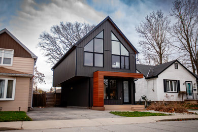 Example of a large 1950s black two-story vinyl house exterior design in Toronto with a black roof