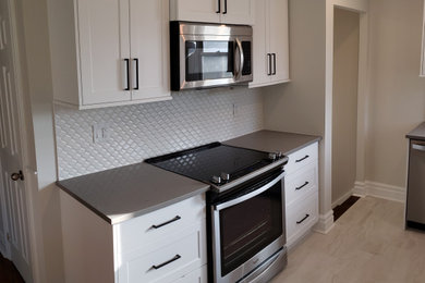 Kitchen - contemporary porcelain tile and beige floor kitchen idea in Toronto with an undermount sink, shaker cabinets, white cabinets, quartz countertops, white backsplash, ceramic backsplash, stainless steel appliances, no island and gray countertops