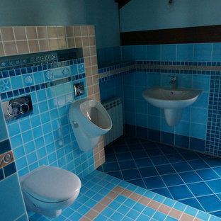 Example of a trendy master blue tile and ceramic tile ceramic floor and turquoise floor freestanding bathtub design in Other with a wall-mount toilet, blue walls, a wall-mount sink, tile countertops and turquoise countertops