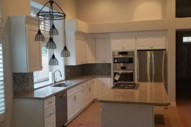 Example of a mid-sized classic u-shaped light wood floor and brown floor enclosed kitchen design in Orange County with an undermount sink, raised-panel cabinets, white cabinets, quartz countertops, multicolored backsplash, mosaic tile backsplash, stainless steel appliances, an island and brown countertops