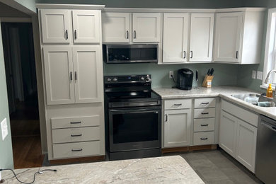 Mid-sized minimalist l-shaped enclosed kitchen photo in Other with white cabinets and laminate countertops