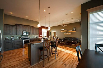Example of a large classic l-shaped light wood floor open concept kitchen design in Cedar Rapids with a double-bowl sink, raised-panel cabinets, stainless steel cabinets, granite countertops, gray backsplash, stone tile backsplash, stainless steel appliances and an island