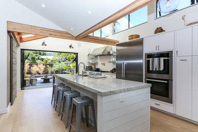 Eat-in kitchen - large contemporary galley light wood floor eat-in kitchen idea in San Francisco with a single-bowl sink, flat-panel cabinets, white cabinets, marble countertops, white backsplash, subway tile backsplash, stainless steel appliances and an island