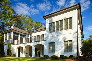 Large elegant white two-story stucco house exterior photo in Other with a hip roof and a shingle roof