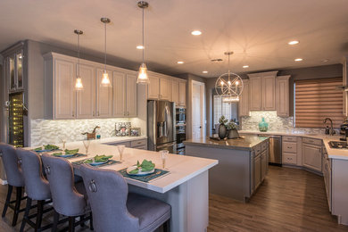 Inspiration for a large transitional open plan kitchen in Phoenix with raised-panel cabinets, grey cabinets, solid surface benchtops, stainless steel appliances, ceramic floors and multiple islands.