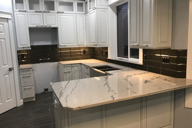 Eat-in kitchen - mid-sized contemporary u-shaped vinyl floor and gray floor eat-in kitchen idea in Portland with a farmhouse sink, raised-panel cabinets, white cabinets, marble countertops, black backsplash, ceramic backsplash, a peninsula and multicolored countertops