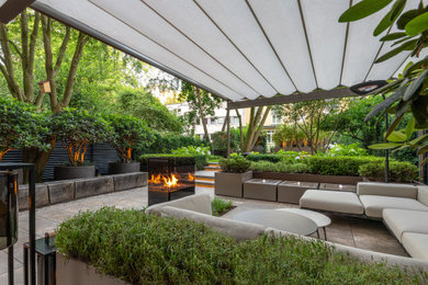 Moderne Pergola mit Feuerstelle und Natursteinplatten in Hamburg