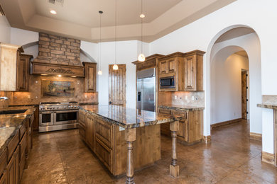 Enclosed kitchen - large craftsman l-shaped concrete floor and brown floor enclosed kitchen idea in Phoenix with a drop-in sink, granite countertops, beige backsplash, stone tile backsplash, stainless steel appliances, raised-panel cabinets, dark wood cabinets and an island