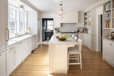 Kitchen - mid-sized traditional l-shaped medium tone wood floor and brown floor kitchen idea in Minneapolis with an undermount sink, white cabinets, gray backsplash, white appliances, an island and white countertops