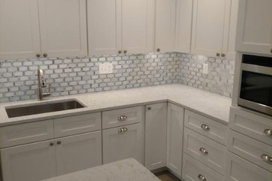 Open concept kitchen - mid-sized transitional l-shaped medium tone wood floor and brown floor open concept kitchen idea in DC Metro with shaker cabinets, white cabinets, marble countertops, an island, an undermount sink, white backsplash, marble backsplash and stainless steel appliances