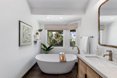Mid-sized minimalist master ceramic tile, brown floor and double-sink bathroom photo in Orange County with flat-panel cabinets, light wood cabinets, a one-piece toilet, white walls, an undermount sink, quartz countertops, a hinged shower door, white countertops and a built-in vanity