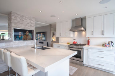 Mid-sized modern galley open plan kitchen in Vancouver with flat-panel cabinets, white cabinets, marble benchtops, white splashback, with island, white benchtop, a double-bowl sink, white appliances, vinyl floors and brown floor.