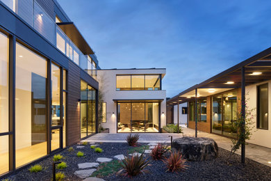 Large minimalist white two-story stucco exterior home photo in San Francisco with a mixed material roof and a gray roof