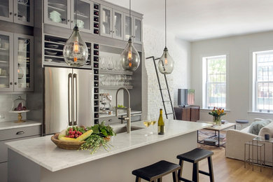 Design ideas for a large transitional l-shaped open plan kitchen in Boston with an undermount sink, glass-front cabinets, grey cabinets, marble benchtops, white splashback, porcelain splashback, stainless steel appliances, light hardwood floors and with island.