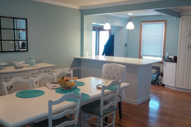 Example of a mid-sized transitional galley light wood floor eat-in kitchen design in Philadelphia with raised-panel cabinets, white cabinets, solid surface countertops, blue backsplash and a peninsula