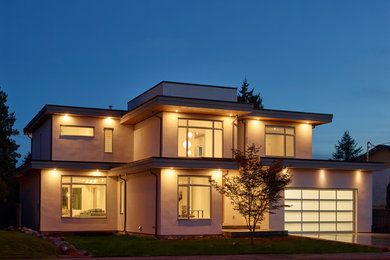 Example of a large trendy three-story stucco exterior home design in Vancouver with a black roof