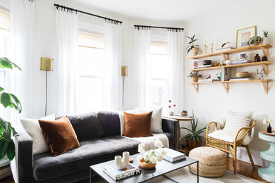 Example of an eclectic medium tone wood floor living room library design in Boston with white walls and no fireplace