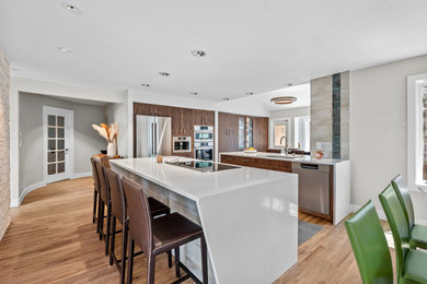 Large trendy galley light wood floor, brown floor and vaulted ceiling eat-in kitchen photo in Denver with an undermount sink, flat-panel cabinets, medium tone wood cabinets, quartz countertops, blue backsplash, porcelain backsplash, stainless steel appliances, two islands and white countertops