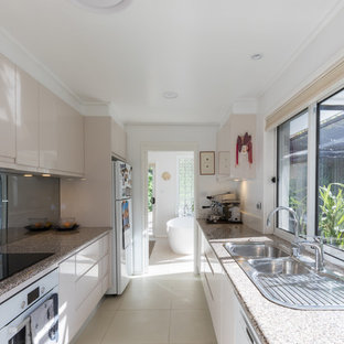 Large modern kitchen pantry designs - Example of a large minimalist galley ceramic floor and beige floor kitchen pantry design in Canberra - Queanbeyan with a double-bowl sink, flat-panel cabinets, beige cabinets, granite countertops, white appliances and no island