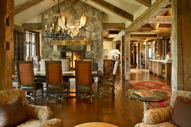 Example of a mountain style dark wood floor great room design in Denver with beige walls, a two-sided fireplace and a stone fireplace