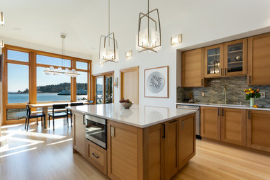 Example of a large u-shaped bamboo floor and vaulted ceiling eat-in kitchen design in Seattle with an undermount sink, recessed-panel cabinets, medium tone wood cabinets, quartz countertops, gray backsplash, glass tile backsplash, stainless steel appliances, an island and white countertops