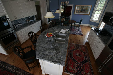 Large country u-shaped eat-in kitchen in New Orleans with a double-bowl sink, raised-panel cabinets, white cabinets, granite benchtops, blue splashback, mosaic tile splashback, stainless steel appliances, medium hardwood floors and with island.