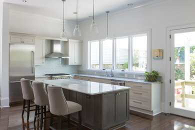Example of a mid-sized transitional l-shaped dark wood floor eat-in kitchen design in New Orleans with white cabinets, multicolored backsplash, mosaic tile backsplash, stainless steel appliances, an island, an undermount sink, shaker cabinets and marble countertops