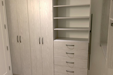 Example of a large trendy gender-neutral walk-in closet design in Vancouver with light wood cabinets