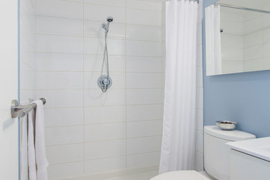 Trendy white tile and ceramic tile porcelain tile and beige floor alcove shower photo in Vancouver with flat-panel cabinets, white cabinets, a two-piece toilet and blue walls