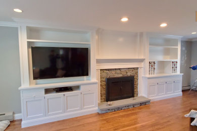 Inspiration for a mid-sized timeless open concept family room remodel in New York with a standard fireplace, a stone fireplace, gray walls and a media wall