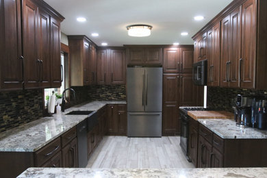 Example of a large classic u-shaped porcelain tile and multicolored floor eat-in kitchen design in Other with a farmhouse sink, dark wood cabinets, granite countertops, multicolored backsplash, glass tile backsplash, stainless steel appliances, an island and multicolored countertops