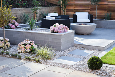 Inspiration for a mid-sized modern backyard full sun garden for summer in West Midlands with a fire feature.