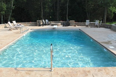 Ejemplo de piscina con fuente minimalista grande rectangular en patio trasero con suelo de hormigón estampado