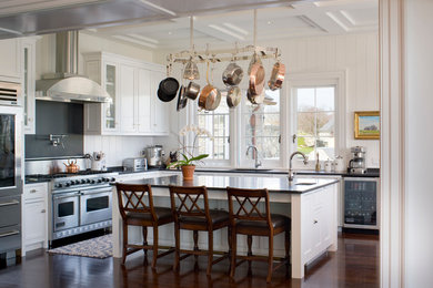 Inspiration for a mid-sized beach style l-shaped kitchen in Providence with recessed-panel cabinets, white cabinets, stainless steel appliances, dark hardwood floors and with island.