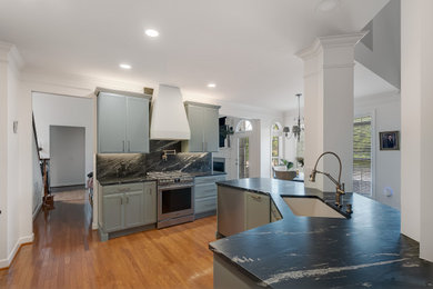 Eat-in kitchen - mid-sized transitional eat-in kitchen idea in Nashville with shaker cabinets, green cabinets, soapstone countertops, black backsplash, an island and black countertops