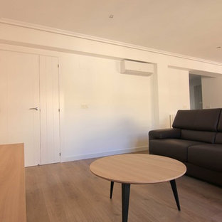 Imagen de salón abierto, mediterráneo, grande, con paredes blancas, suelo laminado y pared multimedia