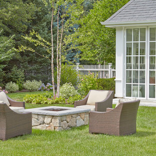 Réalisation d'un grand jardin arrière tradition avec un foyer extérieur, une exposition ensoleillée et des pavés en pierre naturelle.