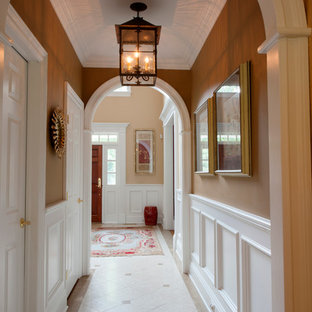 Inredning av en eklektisk stor foajé, med bruna väggar, mellanmörkt trägolv, en enkeldörr och en vit dörr