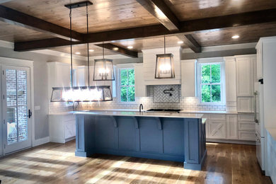 Eat-in kitchen - large farmhouse l-shaped light wood floor and brown floor eat-in kitchen idea in Atlanta with a farmhouse sink, flat-panel cabinets, white cabinets, granite countertops, white backsplash, subway tile backsplash, stainless steel appliances, an island and white countertops