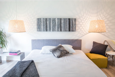 Example of a mid-sized minimalist master medium tone wood floor bedroom design in Other with white walls