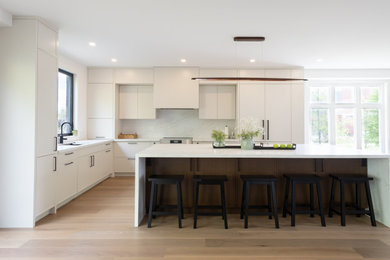 Large l-shaped light wood floor and beige floor open concept kitchen photo in Toronto with white cabinets, quartz countertops, white backsplash, marble backsplash, paneled appliances, an island and white countertops