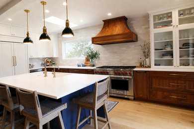 Open concept kitchen - mid-sized coastal l-shaped light wood floor and brown floor open concept kitchen idea in Seattle with an undermount sink, recessed-panel cabinets, medium tone wood cabinets, quartz countertops, gray backsplash, ceramic backsplash, stainless steel appliances, an island and white countertops