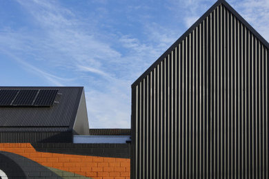 Design ideas for a mid-sized contemporary one-storey black house exterior in Melbourne with a gable roof, a metal roof and a black roof.