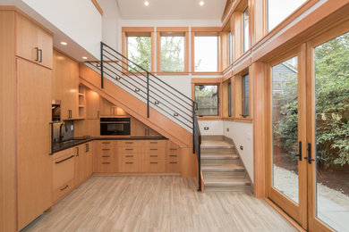 Inspiration for a mid-sized craftsman l-shaped porcelain tile and gray floor open concept kitchen remodel in Portland with an undermount sink, flat-panel cabinets, light wood cabinets, quartzite countertops, black appliances, no island and black countertops