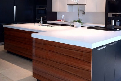Inspiration for a mid-sized contemporary u-shaped eat-in kitchen remodel in Miami with flat-panel cabinets, white backsplash, stainless steel appliances, an island, black cabinets, quartz countertops and stone slab backsplash